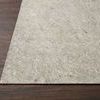 Close-up of rug pad edge on dark wood floor, highlighting fibrous surface texture