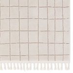 Close-up front view focusing on braided fringe and grid detail on cream rug