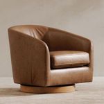 Oscy chair styled in a neutral room setting with light wood swivel base visible