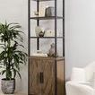 Modern wooden display cabinet with metal frame placed on rug near cream upholstered chair and plant