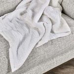 TC Linen Cotton Blend Throw Blanket casually draped on grey textured fabric sofa, showing texture and plush sherpa edge