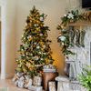 Full view of decorated Christmas tree with olive green mercury glass ornaments and cozy living room fireplace mantel with ...