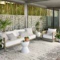 Rainier Ivory / Grey Rug styled in modern outdoor seating area with white sofa, armchair, and plants