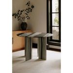 Celia round dining table staged in a room setting with natural light, beige carpet, and wooden cabinet in background