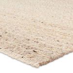 Close-up showing thick, looped shearling texture and woven fringe edge in natural tan tones