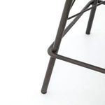 Detail of black-waxed iron stool leg with bent footrest connection and smooth finish