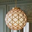 Polyhedron Pendant appearing warm-lit, highlighting the brass metalwork against green decorative wall