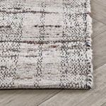 Corner edge view showing tight wool weave and finished selvage on light hardwood floor