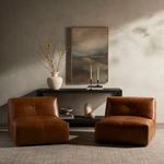 Two camel leather chairs styled in a neutral room with console table, artwork, and minimal decor