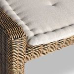 Side profile with slight angle showing full beige cushion on woven rattan