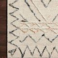 Detailed corner view of wool pile rug on wooden floor highlighting textured loops and color contrast
