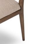 Close-up of tan wood frame joint where seat cushion meets chair leg