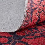 Underside of a different rug with red and navy pattern showing close-stitched edge detail
