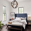 Bed styled in bright white room with wood floors and decorative bench at foot