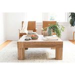 Reclaimed oak coffee table in bright living room next to leather chairs and white walls