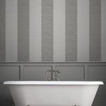 Vertical striped wallpaper hung behind a white bathtub in a styled bathroom setting