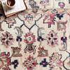 Close-up on floral patterns showing wool texture and colors of the Elka Ivory Multi Rug with a tea cup and book