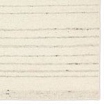 Detailed close-up of rug surface with varying thickness taupe stripes on cream wool background