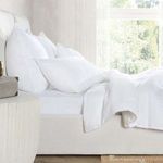 Camille Linen Blend sham styled on bed in bright room with natural light and visible beige upholstered bed frame