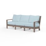 Laguna Sofa with driftwood-finish aluminum frame and light blue cushions, featuring plank arms and curved slat back