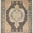 Bhima handknotted rug with medallion pattern in charcoal, blue, cream, and beige tones, fringed edges