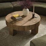 Abaso Round Coffee Table styled in living room with decor including books, candle, and vase