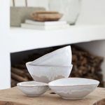 Set of four bowls stacked and arranged on wooden table with rustic fireplace background