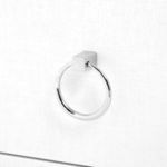 Close-up of shiny silver metal ring pull attached to lower drawer on white lacquered grasscloth side table