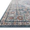 Low angle side view showing the rug's thin profile and detailed border pattern with blue and rust tones