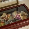 Display box closed with vintage photographs displayed under transparent glass lid on light furniture