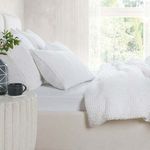 sham styled on bed with matching white waffle-textured bedding in bright natural bedroom setting