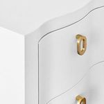 Close-up of textured white finish and unique oval gold handle detail on curved drawer front