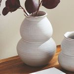Chyrssa Vase styled on a wooden table holding deep red faux leaves against a cream wall
