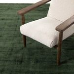 Green rug with beige textured armchair legs showing contrast in materials and color