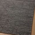 Flat corner view focusing on the rug’s charcoal pattern and tight woven surface on wood floor