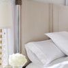 Detailed close-up of illuminated acrylic headpost, beige upholstered headboard, and bedside lamp with white flowers