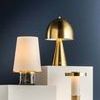 Table lamp styled with two other brass and white lamps on staggered white blocks