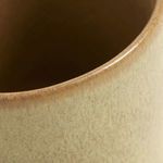 Close-up of beige ceramic cup showing fine speckled glaze texture and glossy finish