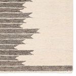 Close-up of rug corner showing gray accent stripe and fringe on the cream background