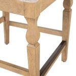 Close-up of Gaston stool’s carved wooden leg and footrest structure with rustic finish