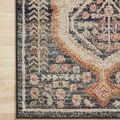 Close-up on rug’s navy and orange border pattern with floral accents on light flooring