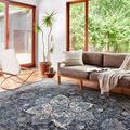 Samra denim rug shown in bright living room under a sofa and chair by large windows with wood flooring