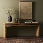 Table in a styled room with dark green wall, pottery, artwork, and patterned rug