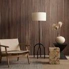 Nador rug shown in a styled room with wooden slat wall, beige chair, black metal floor lamp, and sculptural side tables