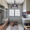 Wall sconce mounted in beige-toned mudroom near window with built-in cabinetry and decorative large pendant light