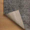 Rug corner lifted to reveal woven backing texture and edge binding