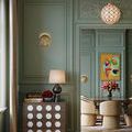 Pendant illuminated in green room hanging above seating area with floral artwork on wall