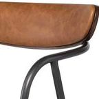 Close-up of desert leather upholstery texture and rounded metal frame detail on backrest