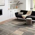 Bowery Storm Taupe Rug styled under black sofa and round concrete coffee table in bright living room