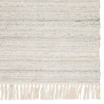 Torre rug styled with wooden side table, glass vase, and rope daybed in bright room